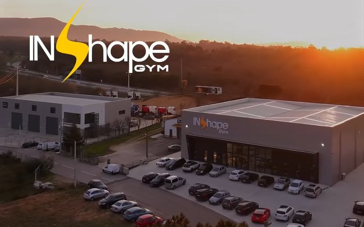 Vista aérea do InShape Gym ao pôr do sol, com o estacionamento à frente